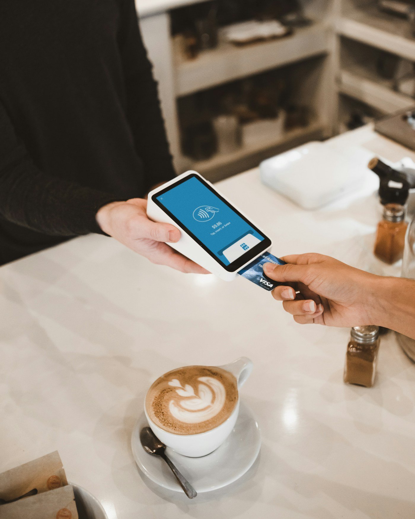 A customer making a card payment beside a cup of coffee